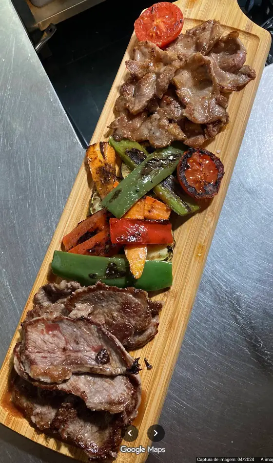 Tábua de carnes grelhadas com legumes e pimentos na brasa