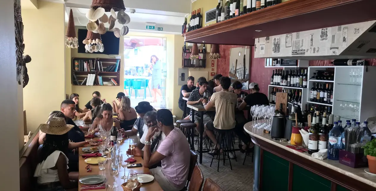 Sala do Cataventos cheia de clientes, com o balcão e a garrafeira ao fundo