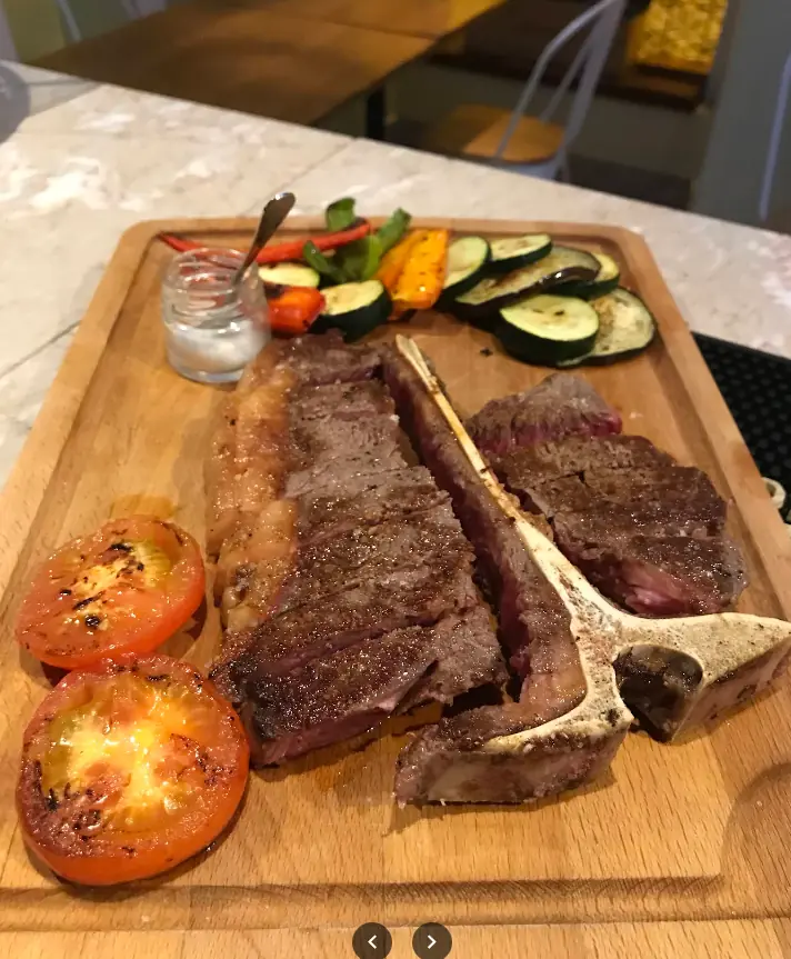 T-bone na brasa numa tábua com legumes e tomate grelhado